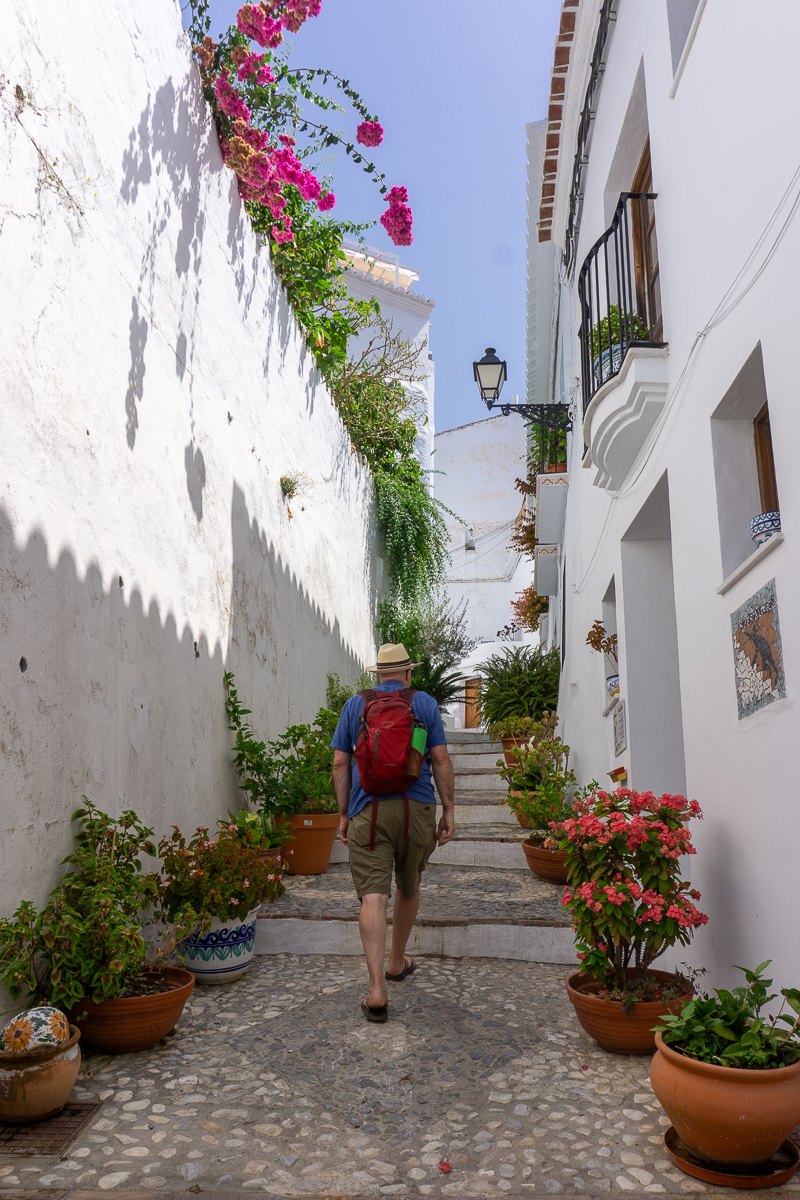 Todd walking up a whitewashed flower-lined alley in Frigiliana, Spain