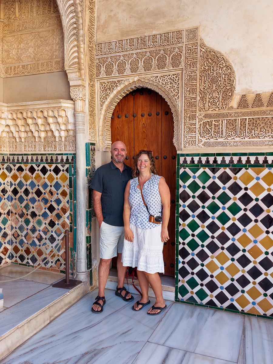 Mairin and Todd in front of carved Moorish arches and tilework at the Alhambra in Granada, Spain