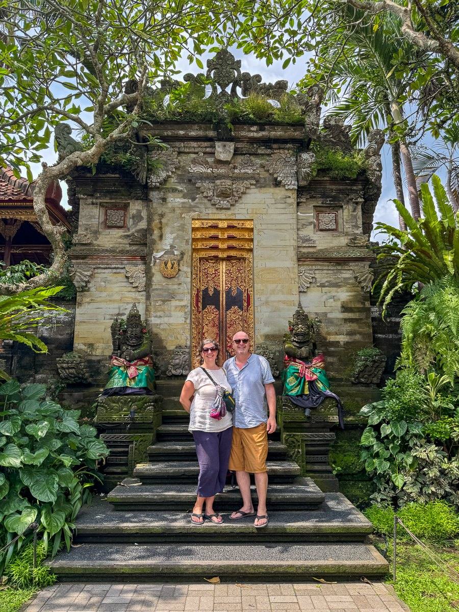 Mairin and Todd on the steps of an ornate carved Balinese temple gate near Ubud, Bali