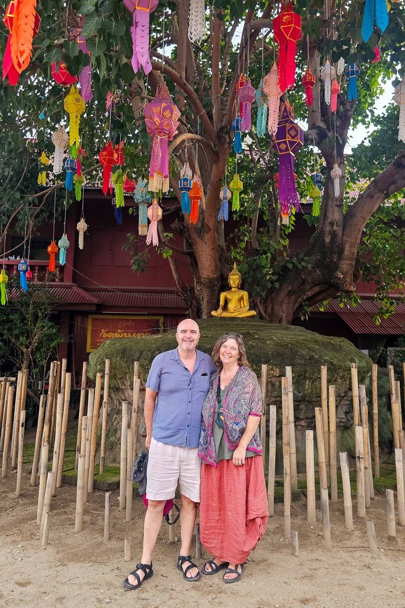 Mairin and Todd under a tree hung with colourful paper lanterns at a temple in Chiang Mai, Thailand