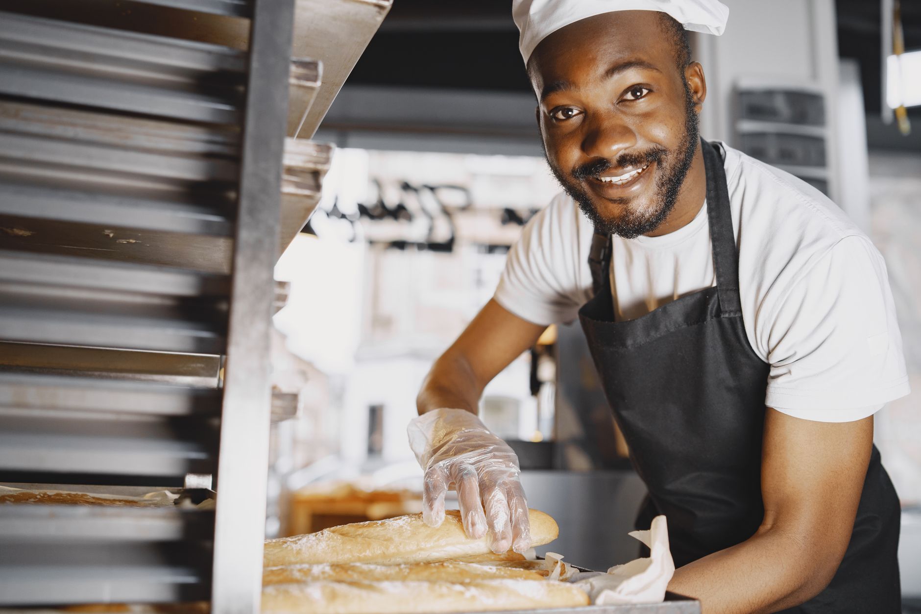 A baker handling fresh baguettes at a bakery