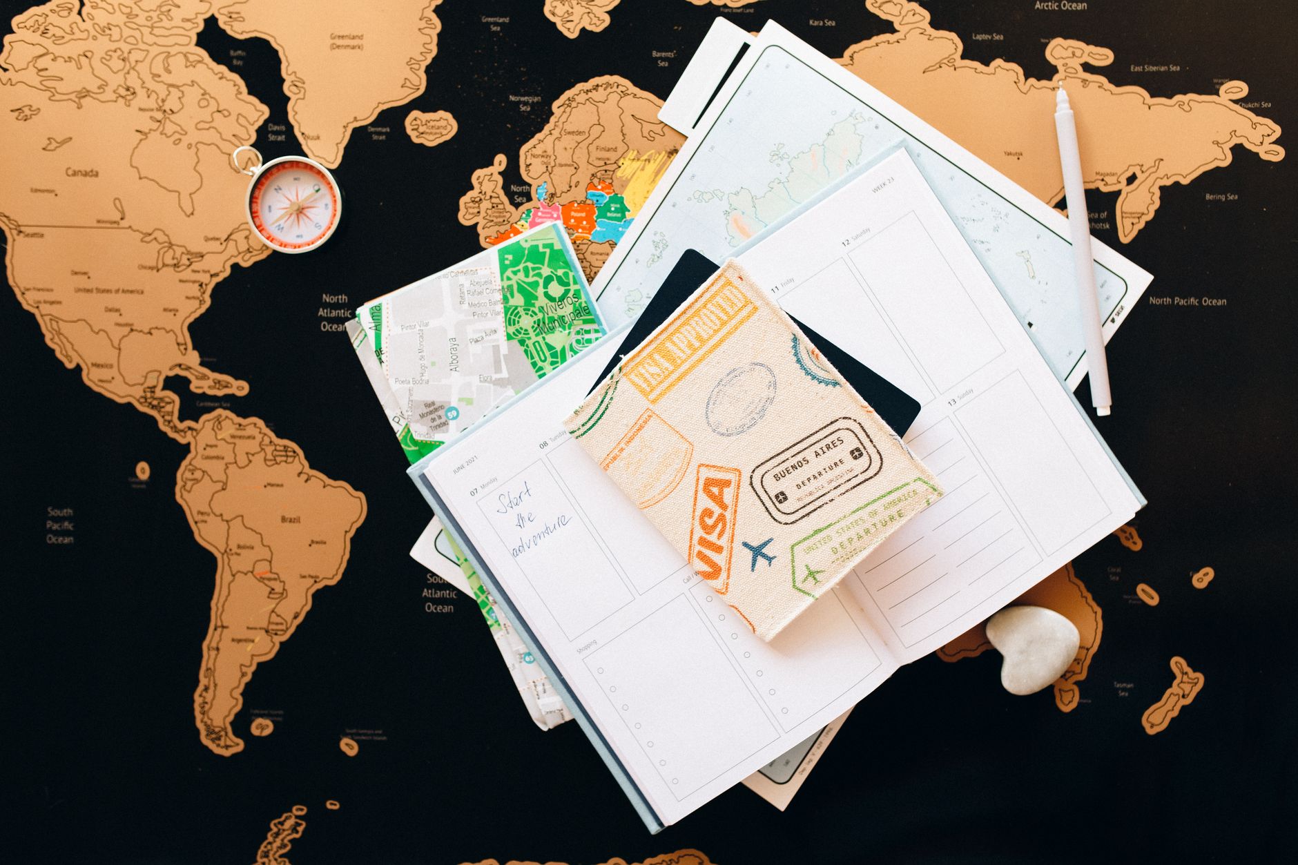 A world map, an open journal and a coffee on a wooden desk
