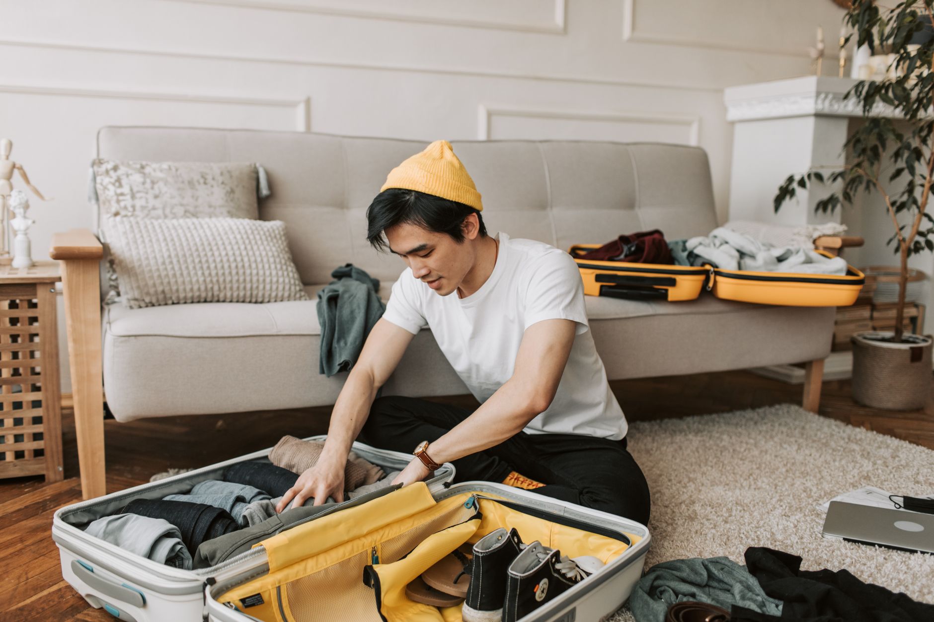 A traveler packing a small bag in a calm, bright room