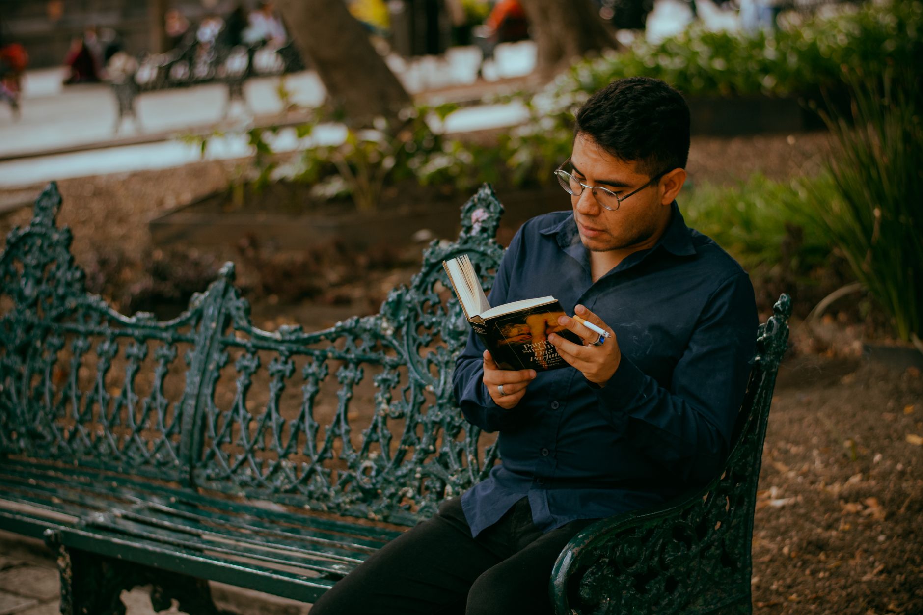 A person reading a book on a bench outdoors
