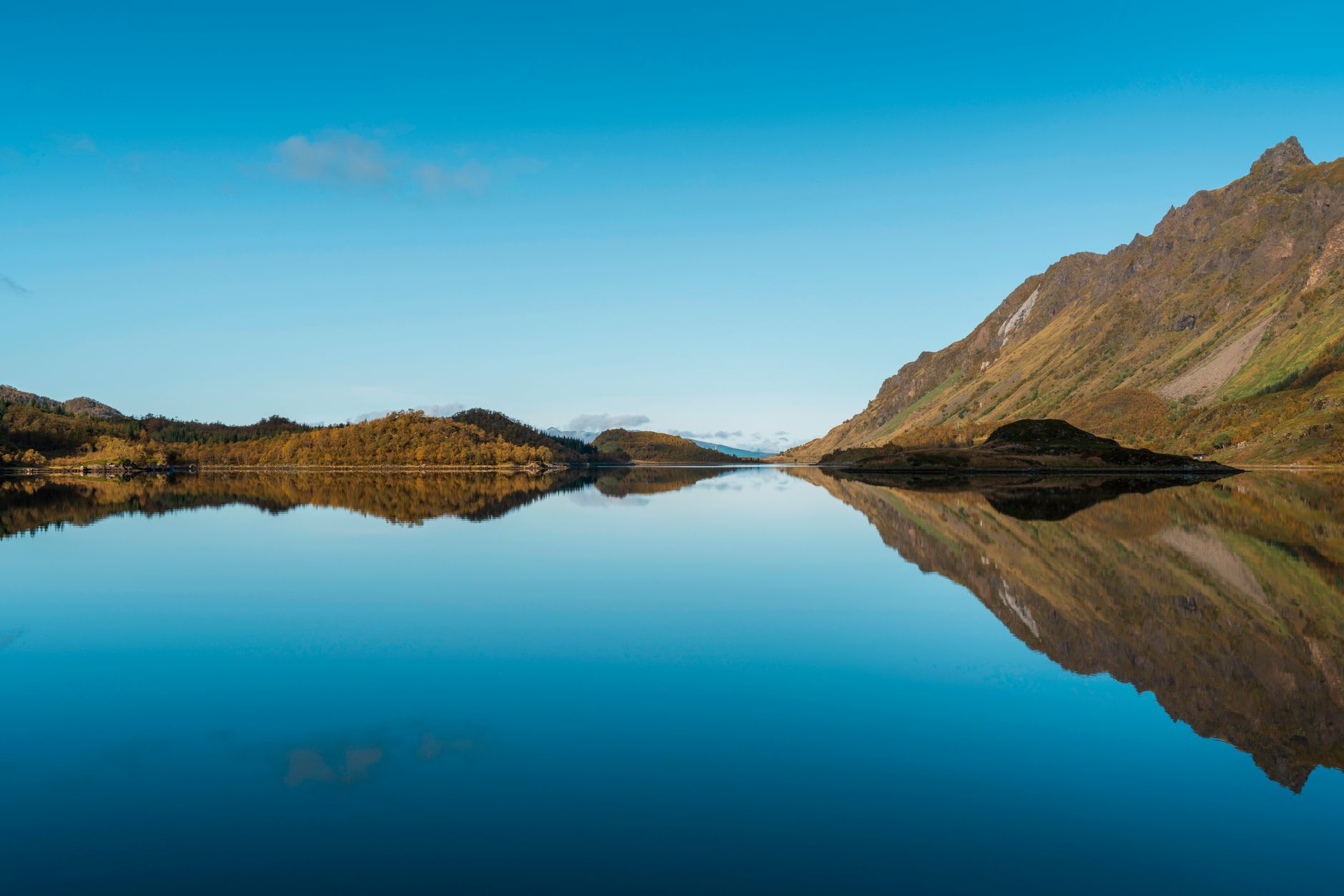 A still mountain lake mirroring green hills, no people in sight