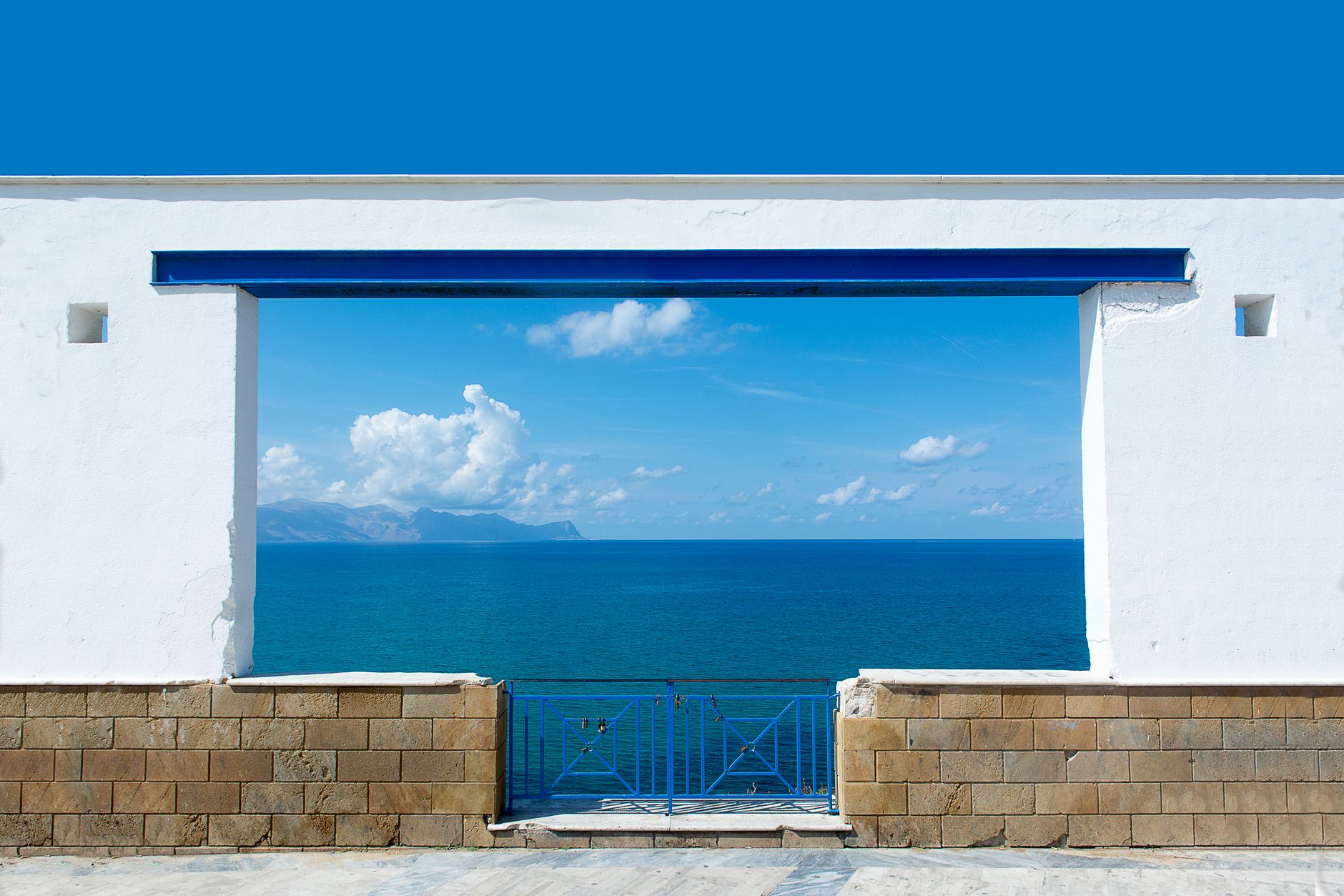 Open shutters framing a calm blue sea view